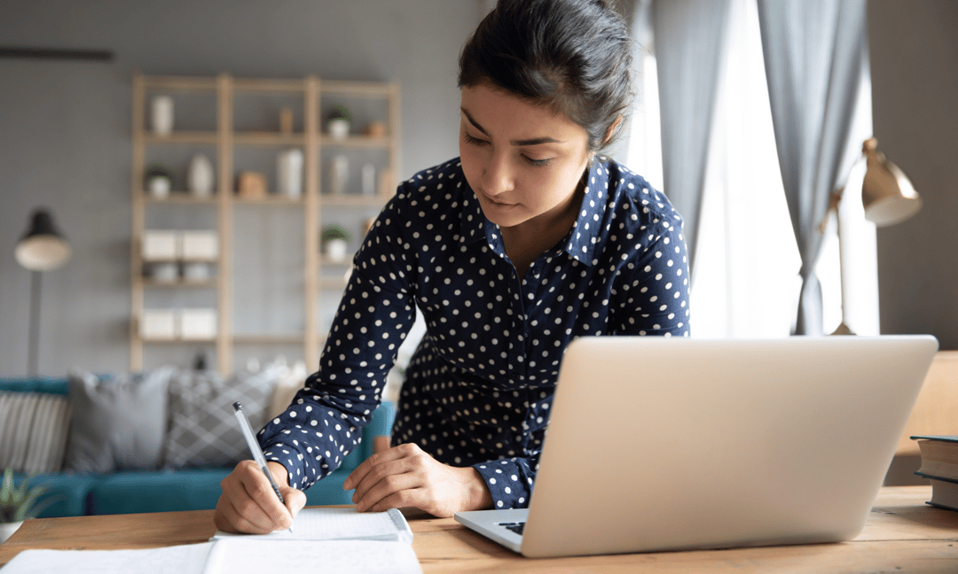 student writing with computer and notepad